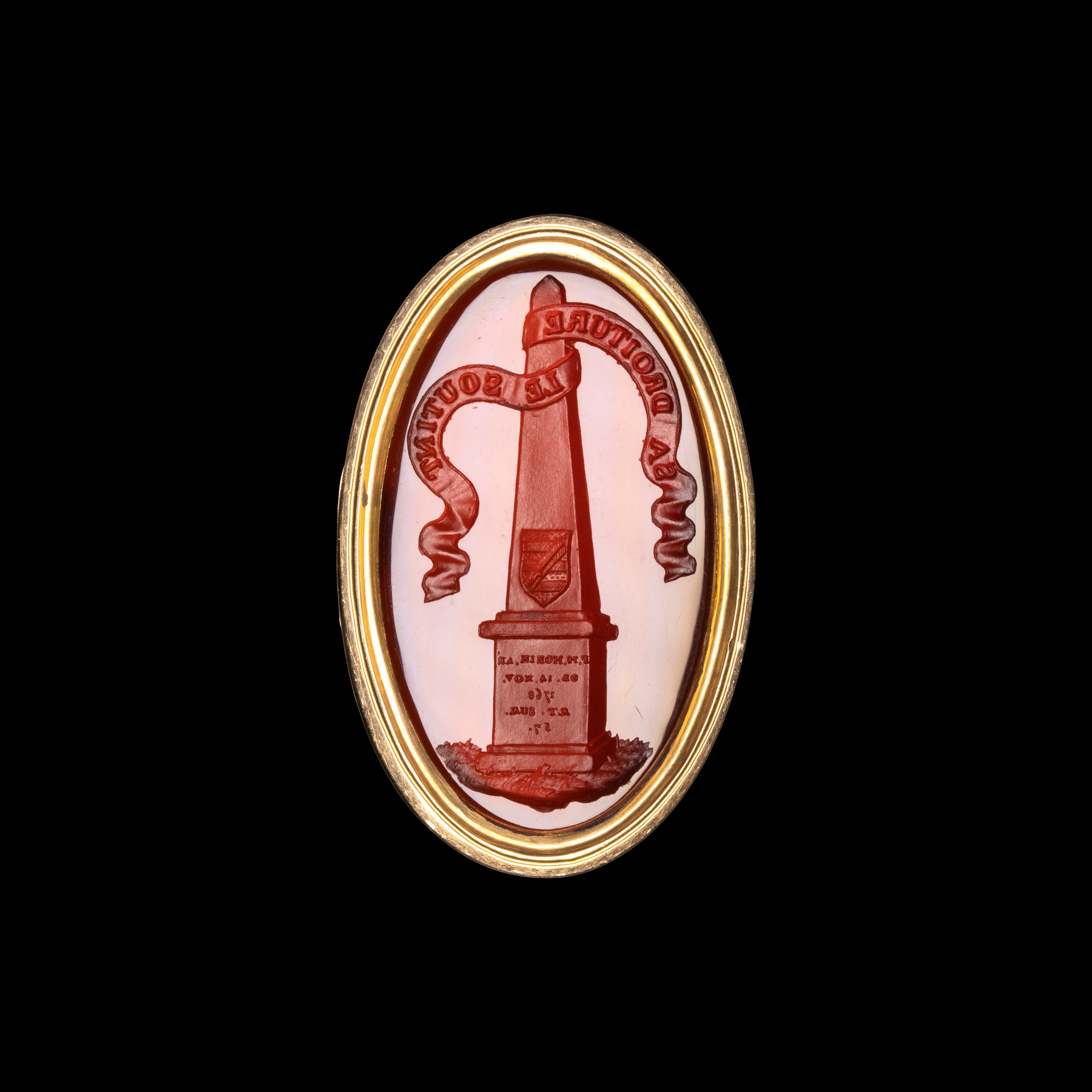 A gold ring set with a Grand Tour carnelian intaglio. Obelisk with coat arms.